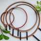 Round circle single hoop wooden indoor plant trellises in four sizes stacked on one another on white background.