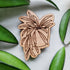 Handcrafted magnet featuring a hoya wayetii engraved in cherry wood against a white background and leaves from the plant.