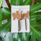 Set of three cat silhouette decorative plant stakes show in product packaging against a monstera leaf background.
