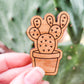 Handcrafted magnet featuring an opuntia cactus engraved in cherry wood held in hand for size perspective. 