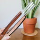 One wooden stand with curved sides holding a clear test tubes held in hand for size perspective.