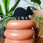 Standard size Triceratops plant stake made from black acrylic displayed in a 4 inch pot with a houseplant.