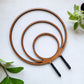 Round circle triple hoop wooden indoor plant trellis with rubber dipped stakes on white background.